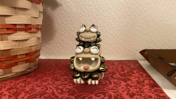 オスとメスが仲良くおんぶしている金のシーサー